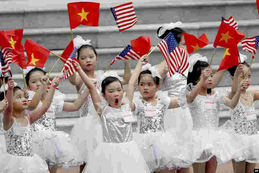 ក្មេងៗវៀតណាមបក់ទង់ជាតិ នៅមុនពិធីទទួលស្វាគមន៍លោកប្រធានាធិបតីអាមេរិក ដូណាល់ ត្រាំ នៅវិមានប្រធានាធិបតី នៅក្នុងក្រុងហាណូយ ប្រទេសវៀតណាម។