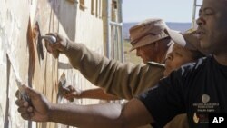 Members from the South African correctional service repair a wall at a school where former South African President Nelson Mandela went as a child as they celebrate his birthday in Qunu, South Africa, Wednesday, July 18, 2012.