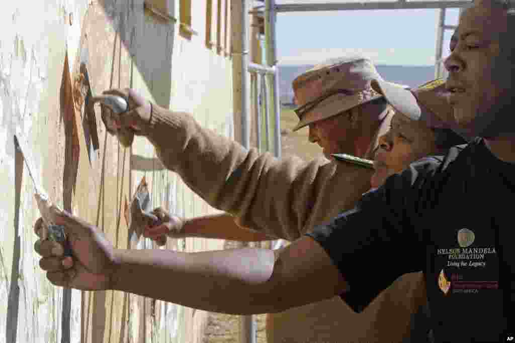 Members from the South African correctional service repair a wall at a school where former South African President Nelson Mandela went as a child as they celebrate his birthday in Qunu, South Africa, Wednesday, July 18, 2012.