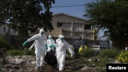 A burial team wearing protective clothing, remove a body of a person suspected of having died of the Ebola virus, in Freetown September 28, 2014.