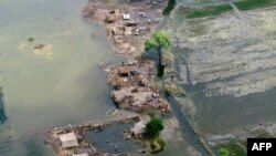 Pakistani villagers seek refuge on a dry patch in the flood-hit Jacobabad district of Sindh province, September 17, 2012. 