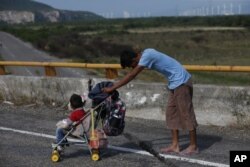 Un migrante empuja un carro de bebé por una carretera mientras una caravana de miles de migrantes centroamericanos sigue su lento avance hacia la frontera con Estados Unidos, entre Niltepec y Juchitan, en el estado de Oaxaca, México, el 30 de octubre de 2018.