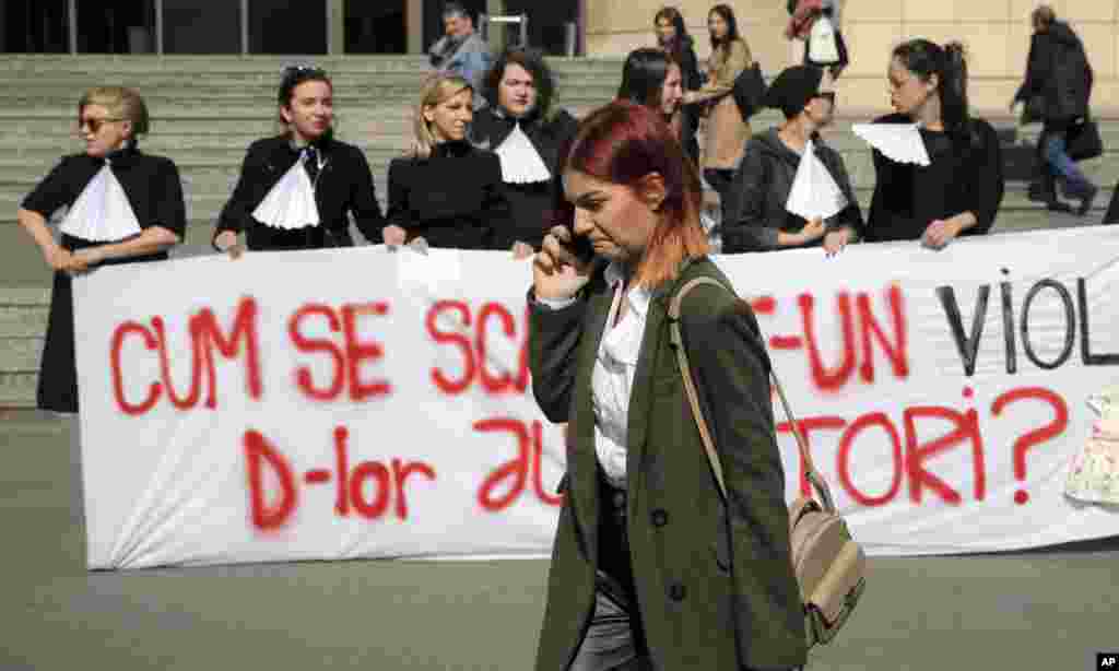 یک زن از مقابل گروهی از زنان معترض در بخارست رومانی می گذرد. این زنان می گویند دستگاه قضایی رومانی مردان آزارگر جنسی را به محکومیت های سبک یا حتی تعلیقی محکوم می کند که کافی نیست.&nbsp;