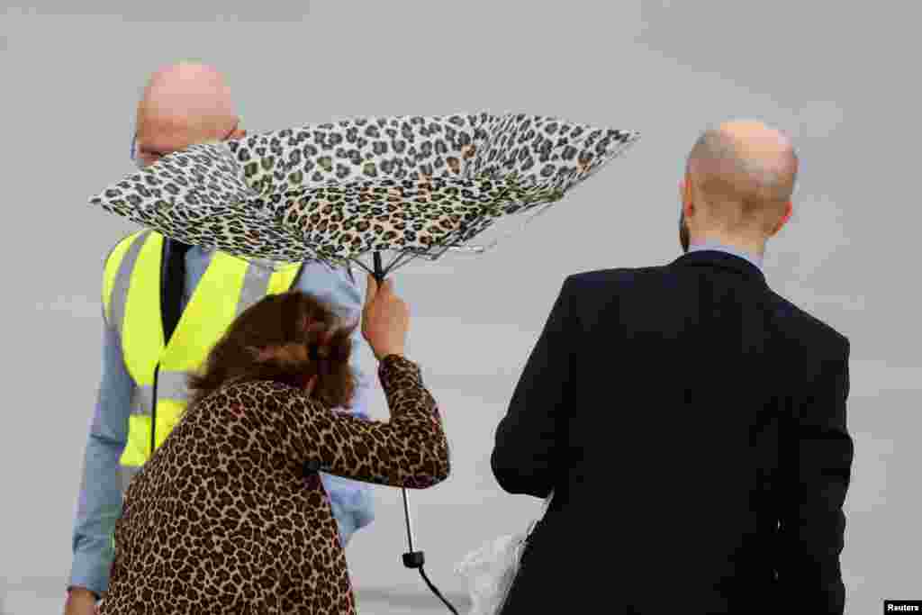 People wait in the rain at the airport ahead of the arrivals of G-20 leaders in Osaka, Japan.