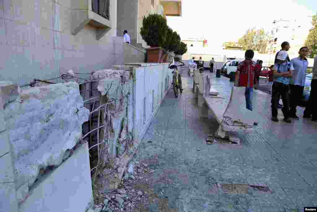 Residents inspect damage from mortar bombs that landed in Badr al-Din al-Hussein school complex, a religious college in Bab Saghir, Damascus, April 29, 2014.