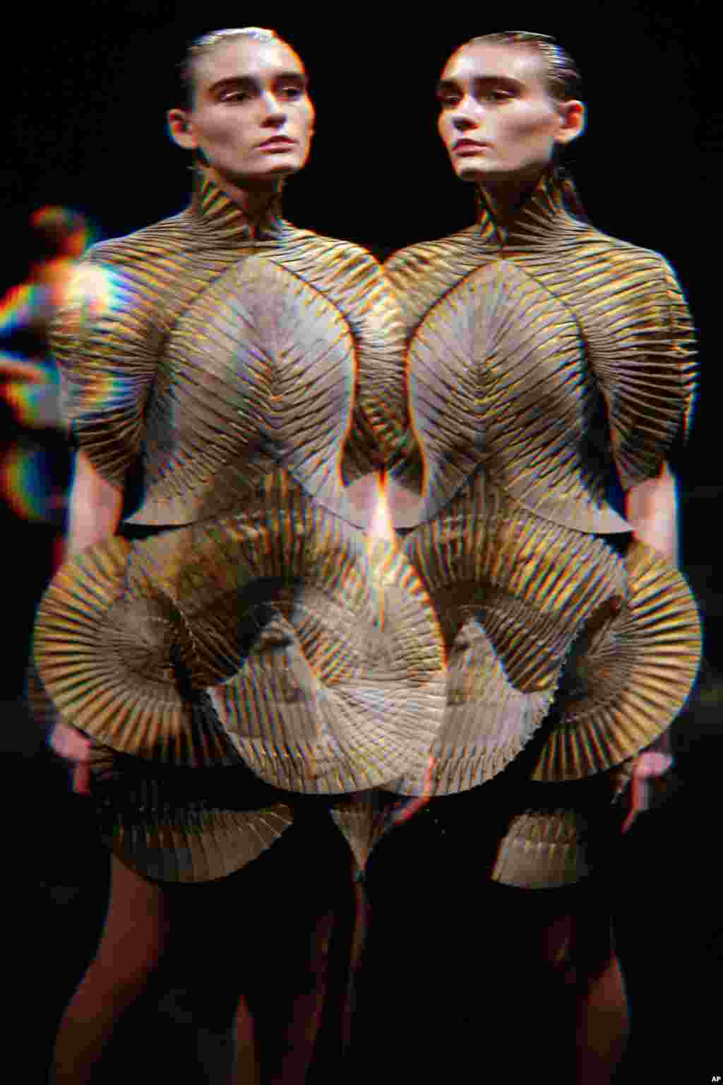 Modelo, vista através de espelho distorcido, apresentamdo última criação de Iris Van Herpen num desfile em Paris.
