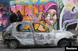 A burned car stands on a street after a previous day's protest against the increase in subway ticket prices in Santiago, Chile, October 20, 2019.