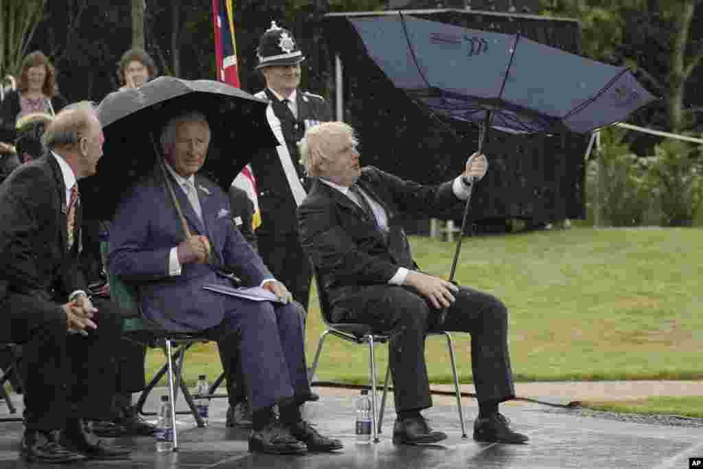 Britain&#39;s Prince Charles, center, and Prime Minister Boris Johnson, right, shelter from rain during the unveiling of the UK Police Memorial at the National Memorial Arboretum at Alrewas, England.