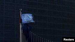 FILE - A European Union flag flutters outside EU Commission headquarters in Brussels, Belgium, Jan. 12, 2016.