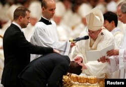 Pope Francis baptizes a man as he leads the Easter vigil Mass in Saint Peter's Basilica at the Vatican, March 31, 2018.