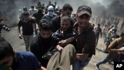 Palestinian protesters carry an injured man who was shot by Israeli troops during a protest at the Gaza Strip's border with Israel, May 14, 2018.