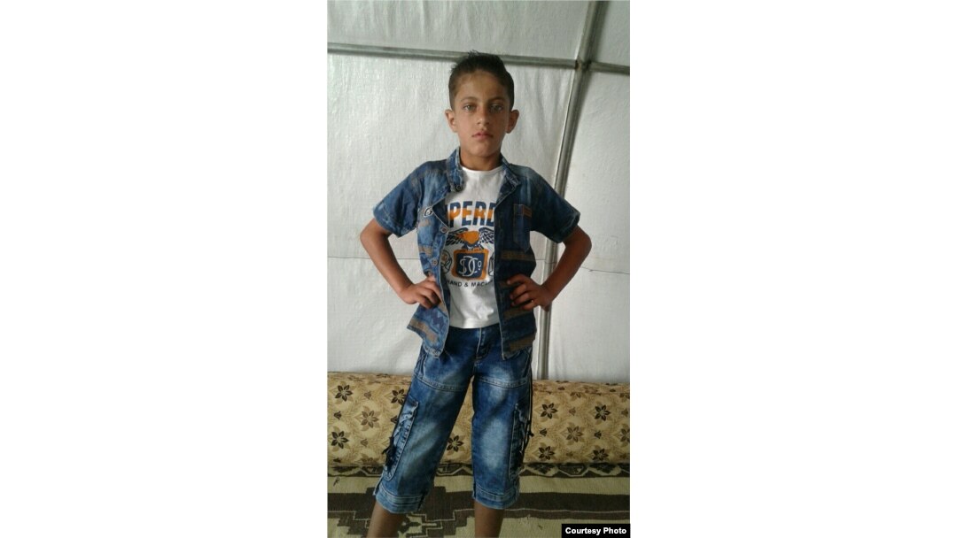 Khaled poses for a picture taken by his mother in their tent inside a refugee camp for orphans, in Idlib's countryside.