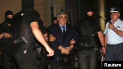 FILE - Extreme-right Golden Dawn party leader Nikolaos Michaloliakos is escorted by anti-terrorism police officers into a court house in Athens October 2, 2013. 
