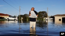 A man walks through a flooded street from Hurricane Irma after retrieving his uniform from his house to return to work at a supermarket in Fort Myers, Florida, Sept. 12, 2017.