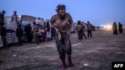 A man suspected of belonging to the Islamic State group walks past members of the Kurdish-led Syrian Democratic Forces just after leaving IS' last holdout of Baghuz, in the eastern Syrian province of Deir Ezzor, March 4, 2019. 