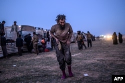 A man suspected of belonging to the Islamic State group walks past members of the Kurdish-led Syrian Democratic Forces just after leaving IS' last holdout of Baghuz, in the eastern Syrian province of Deir Ezzor on March 4, 2019.