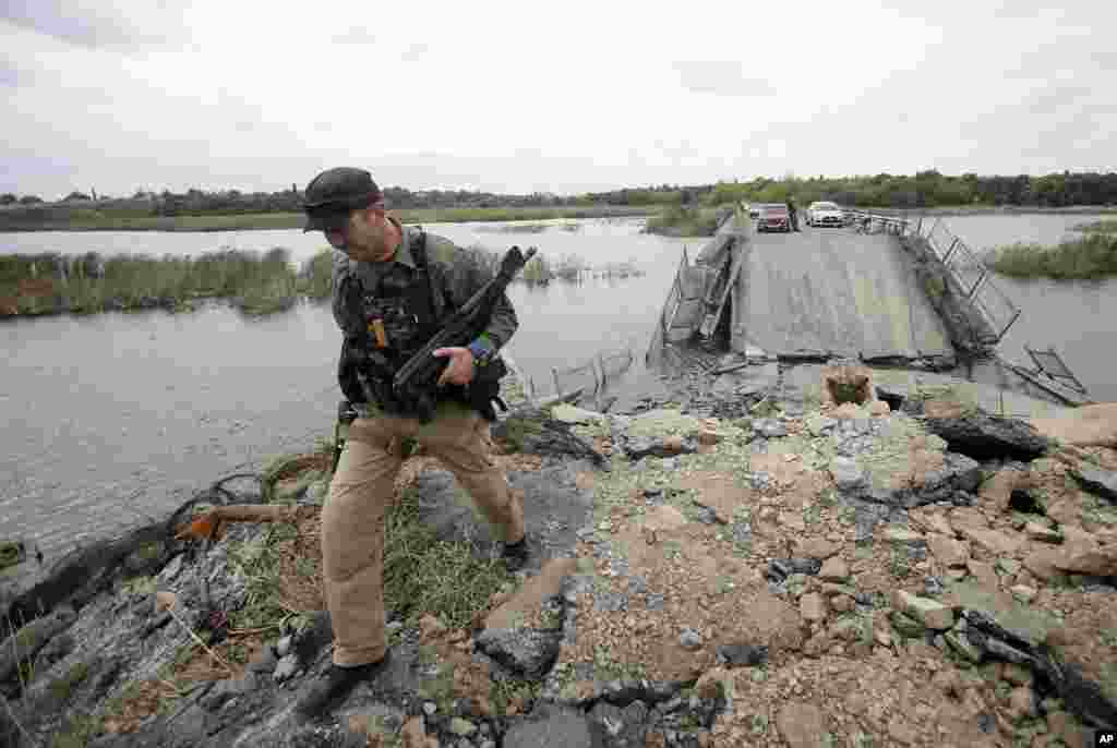 A Pro-Russian rebel guards a destroyed bridge in the village of Nyzhnya Krynka, eastern Ukraine, Sept. 23, 2014.