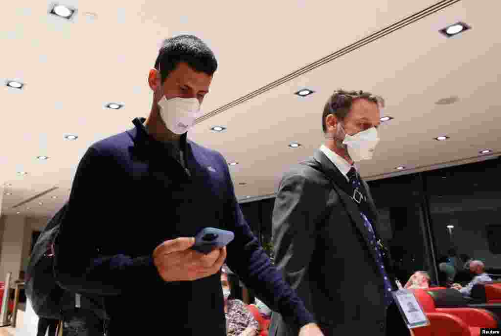 Serbian tennis player Novak Djokovic, left, walks in Melbourne Airport before boarding a flight, after the Federal Court upheld a government decision to cancel his visa to play in the Australian Open, in Melbourne.