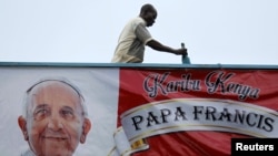 Un voluntario pinta la pared cerca de un cartel dando la bienvenida al papa Francisco en la Universidad de Nairobi, el martes, 24 de noviembre de 2015.