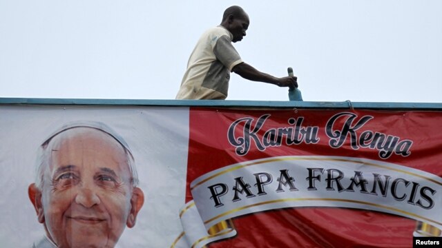 Un voluntario pinta la pared cerca de un cartel dando la bienvenida al papa Francisco en la Universidad de Nairobi, el martes, 24 de noviembre de 2015.
