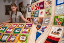 High school student Madeleine Fugate poses with several of her quilts, part of the COVID Memorial Quilt, at her home in Los Angeles, California, Oct. 27, 2021.