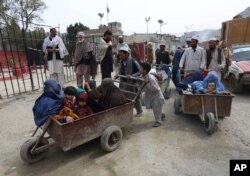 FILE - Afghan women and children sit in a cart pushed by a man as they enter Afghanistan through Pakistan's border crossing in Torkham, east of Kabul, Afghanistan, March. 11, 2015.