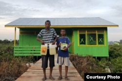 Seorang transmigran dan anaknya di depan rumah mereka di Kalimantan Utara. (Foto: Kemendes PDTT)
