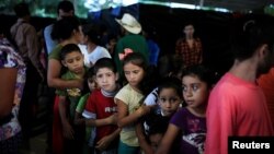  Children line up at dinner time at a shelter for displaced people from El Castano village in the town of Caluco, El Salvador, Sept. 26, 2016. 