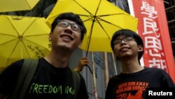 Lãnh đạo sinh viên Joshua Wong (phải) và Nathan Law mỉm cười trước những người ủng hộ cầm ô dù màu vàng, biểu tượng của phong trào Chiếm Trung, bên ngoài một đồn cảnh sát ở Hồng Kông, ngày 14/7/2015.