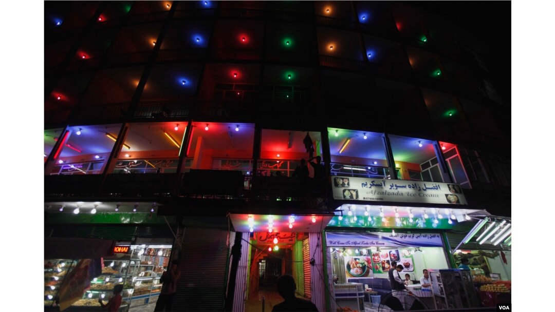 Afghans walk past a lit up guest house and restaurants at a street in Kabul (Photo: AP)