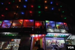Afghans walk past a lit up guest house and restaurants at a street in Kabul (Photo: AP)