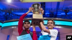 Ansun Sujoe, 13, of Fort Worth, Texas, left, and Sriram Hathwar, 14, of Painted Post, N.Y., raise the championship trophy after being named co-champions of the National Spelling Bee, on Thursday, May 29, 2014.