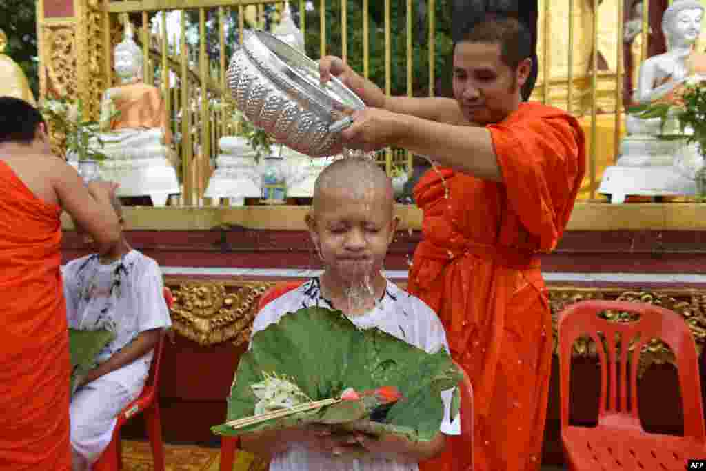 Seorang biksu Budha memandikan kepala anak laki-laki Thailand anggota tim sepak bola &quot;Wild Boars&quot; di kuil Buddha Phra That Doi Wao, distrik Mae Sai, provinsi Chiang Rai dalam upacara penahbisan agama.