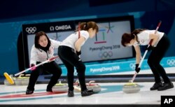 Japan skip Satsuki Fujisawa, left, watches her teammates sweep the ice during a women's curling match against Britain at the 2018 Winter Olympics in Gangneung, South Korea, Feb. 20, 2018.
