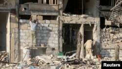 A man rebuilds a wall of a damaged building in the rebel held al-Katerji district in Aleppo, Syria, Aug. 13, 2016.