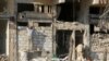 FILE - A man rebuilds a wall of a damaged building in the rebel held al-Katerji district in Aleppo, Syria, Aug. 13, 2016.