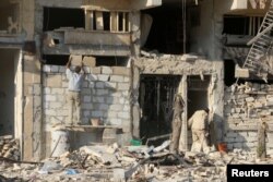 A man rebuilds a wall of a damaged building in the rebel held al-Katerji district in Aleppo, Syria, Aug. 13, 2016.