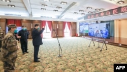 资料照：戴着口罩的中国国家主席习近平视察火神山医院时通过视频向新冠病毒感染者和医护人员招手。（2020年3月10日）