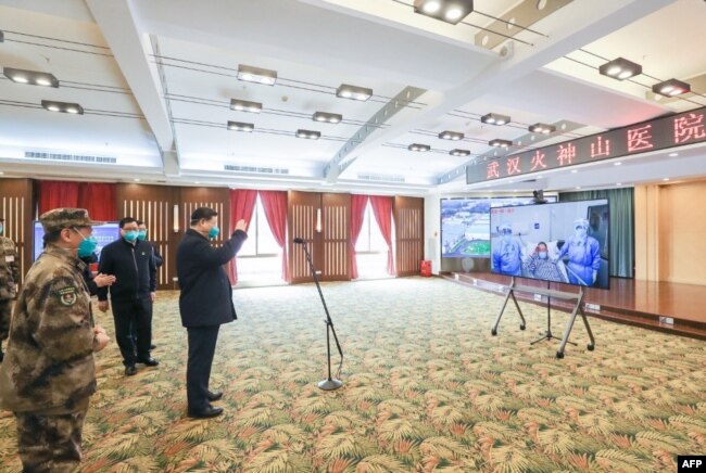 戴着口罩的中国国家主席习近平视察火神山医院时通过视频向新冠病毒感染者和医护人员招手。(2020年3月10日)