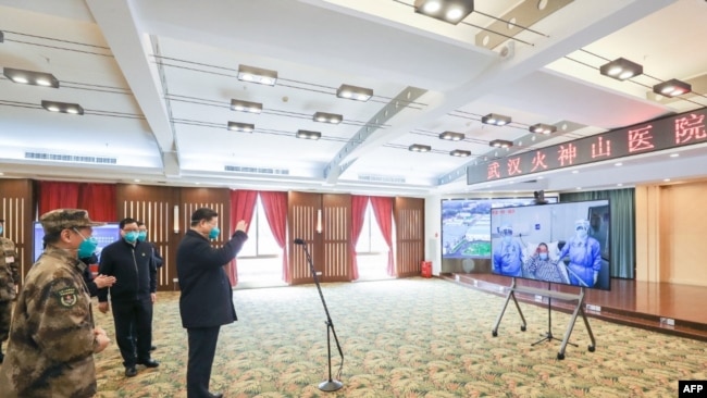 戴着口罩的中国国家主席习近平视察火神山医院时通过视频向新冠病毒感染者和医护人员招手。(2020年3月10日)