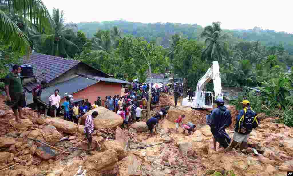 Sri Lankans watch military rescue efforts at the site of a landslide at Bellana village in Kalutara district, Sri Lanka.