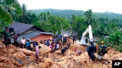 Sri Lankans watch military rescue efforts at the site of a landslide at Bellana village in Kalutara district, Sri Lanka.