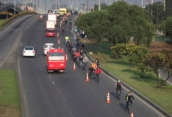 Commuters, wearing protective masks, ride their bicycles in Bogota, Colombia, Tuesday, March 17, 2020.