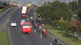 Commuters, wearing protective masks, ride their bicycles in Bogota, Colombia, Tuesday, March 17, 2020.