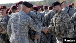 FILE - A Latvian army officer (R) shakes hands with his U.S. counterpart as a contingent of U.S. Army paratroopers arrive at the airport in Riga, Latvia, April 24, 2014.
