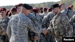 FILE - A Latvian army officer (R) shakes hands with his U.S. counterpart as a contingent of U.S. Army paratroopers arrive at the airport in Riga April 24, 2014.