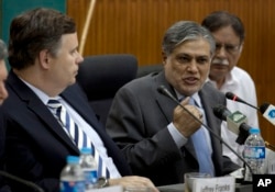 FILE - Then-Pakistani Finance Minister Muhammad Ishaq Dar, center, addresses a news conference with Jeffrey Franks, left, who then was the IMF mission chief for Pakistan, at the finance ministry in Islamabad, Pakistan, July 4, 2013. At the time, Pakistan and the IMF reached agreement on a bailout plan.