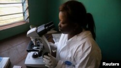 FILE - A laboratory worker uses a microscope at the health center in the commune of Wangata during a vaccination campaign against the outbreak of Ebola, in Mbandaka, Democratic Republic of the Congo, May 23, 2018. 
