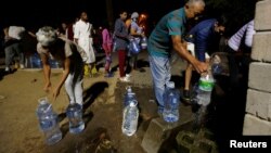 Les gens font la queue pour recueillir l'eau d'une source dans la banlieue de Newlands alors que les craintes sur la crise de l'eau de la ville s'intensifient au Cap, en Afrique du Sud, le 25 janvier 2018.