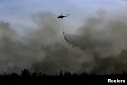 FILE - A helicopter from the Indonesian National Disaster Management agency (BNPB) drops water on a fire in Ogan Ilir, near Palembang, South Sumatra, Indonesia, Aug. 11, 2016, in this photo taken by Antara Foto.